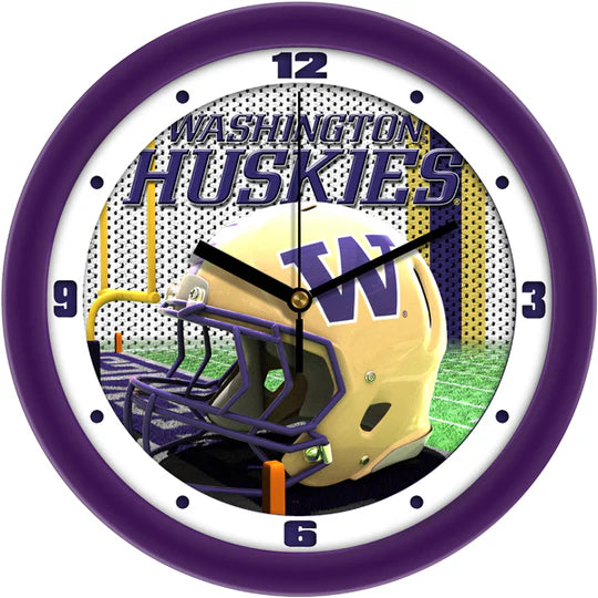 A wall clock featuring the Washington Huskies football helmet design with a predominantly purple background, mineral glass crystal face, and a yellow football helmet graphic in the center.