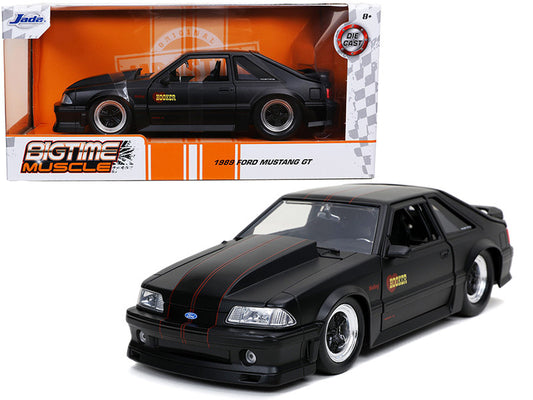 1989 Ford Mustang GT 'Hooker' diecast model, matte black with red stripes, 1/24 scale, detailed, opening parts, original packaging.