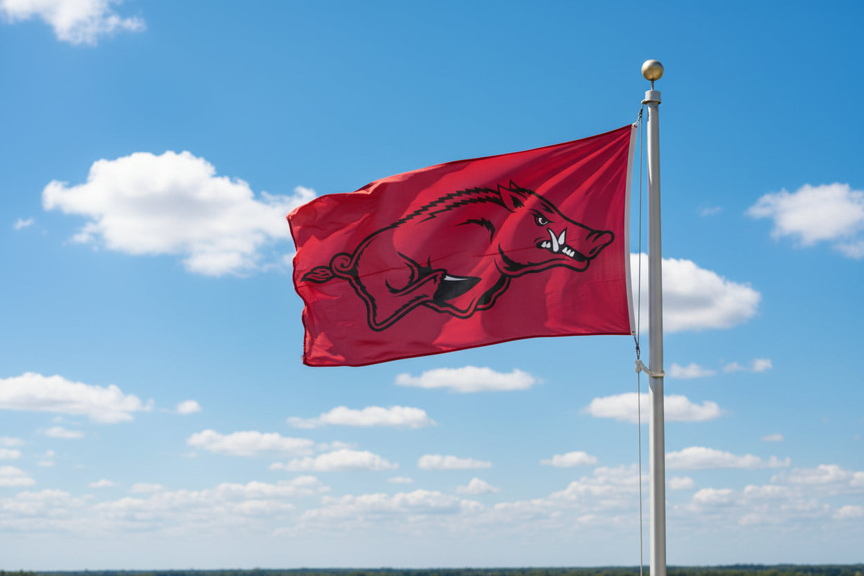 Arkansas Razorbacks red 3' x 5' flag flying from flagpole with partly cloudy sky.